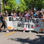 A group of diverse people carrying a banner that says, "Black Lives Matter"