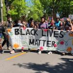 A group of diverse people carrying a banner that says, "Black Lives Matter"